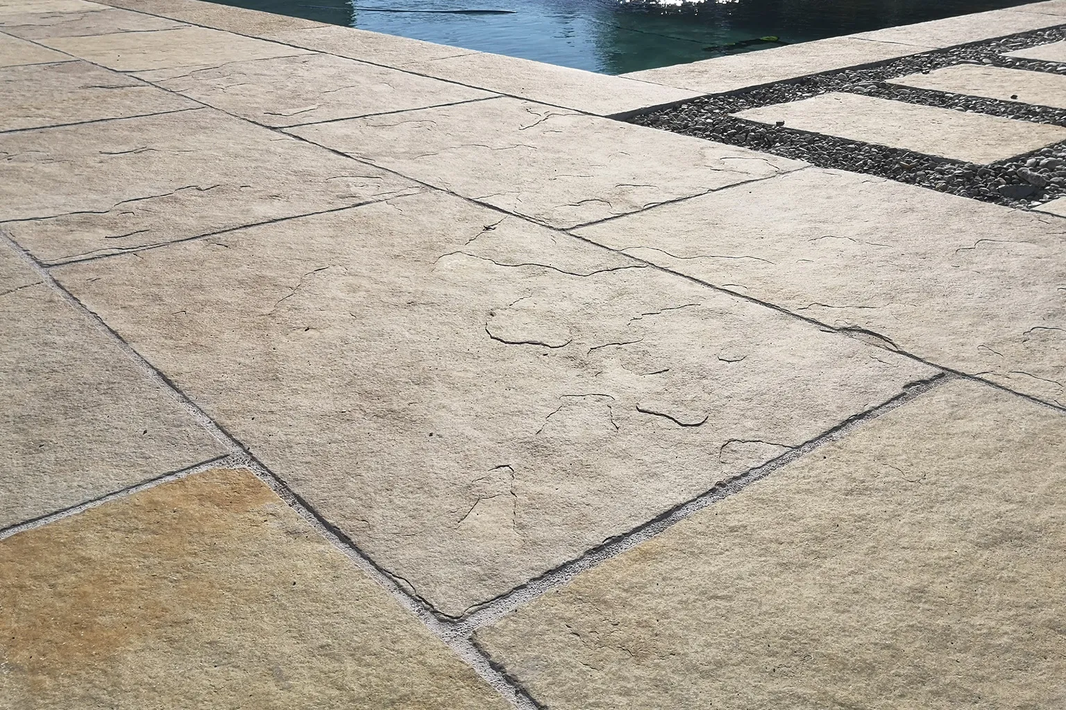 Naturstein-Poolterrasse mit flachen Platten am Wasser